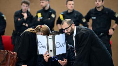 Bild: Udo Güldner
Einer der Angeklagten bespricht sich mit seinen beiden Verteidigern hinter einem Aktenordner.