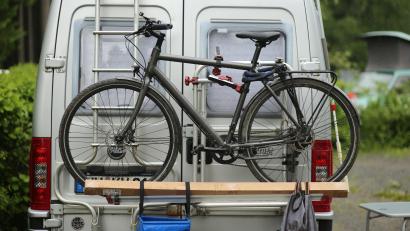 Symbolbild: Matthias Bein/dpa
Ein Wohnmobil, an dem ein Fahrrad befestigt ist, steht auf einem Campingplatz. Vor Beginn der Pfingstferien bietet die Amberger Verkehrspolizei Tipps für Camper an und wiegt auch deren Fahrzeuge.