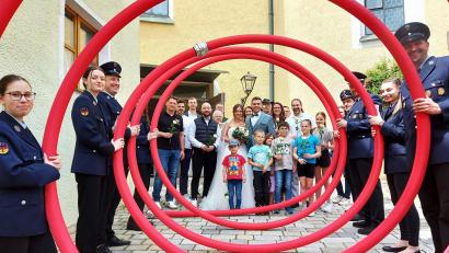 Bild: lg
Das Hochzeitspaar mit den Gratulanten von Stadtrat und Junger Union vor dem Durchschreiten der riesigen roten Schlauchspirale, die die Feuerwehrleute am Kirchenaufgang aufgebaut hatten.