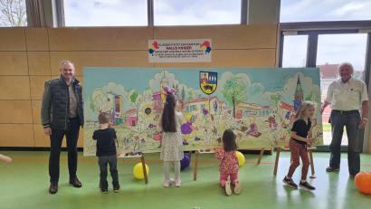 Bild: wec
Bürgermeister Erich Meidinger (links) und Hans-Georg Hierl (rechts) am bunten Gemeinde-Gemälde auf dem verschiedene vom Künstler skizzierte Wahrzeichen von den Kindern ausgemalt werden.