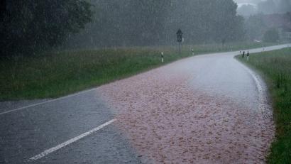 Bild: Daniel Vogl/dpa
Das Regenwasser spült Erde über eine Straße. Regenwolken ziehen über Südthüringen und es regnet stark.