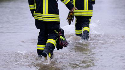 Bild: Sven Hoppe/dpa
Feuerwehrleute gehen über eine überflutet Straße.