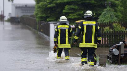 Bild: Sven Hoppe/dpa
Feuerwehrleute gehen über eine überflutet Straße in Dasing.