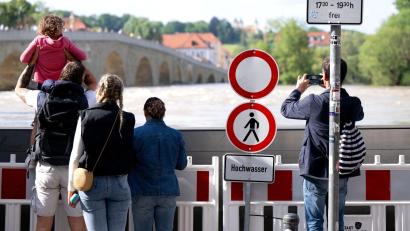 Bild: Sven Hoppe/dpa
Menschen schauen sich in der Altstadt am Donauufer hinter einer Schutzwand das Hochwasser an.