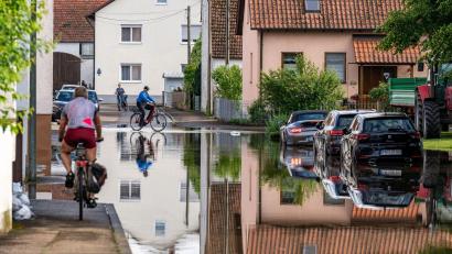 Bild: Armin Weigel/dpa
Radler fahren durch eine überflutete Straße.