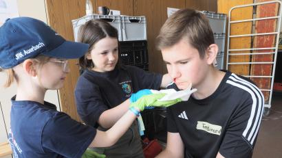 Bild: kek
Praktische Erste Hilfe: Zwei Bambini aus Auerbach helfen einem jungen Mann mit (simuliertem) Nasenbluten.