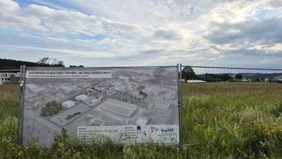 Bild: Lowak
Ein Plakat am Bauzaun des Grundstücks im Gewerbepark Neuhaus kündigt das Großprojekt des Bayerischen Zentrums für besondere Einsatzlagen an.