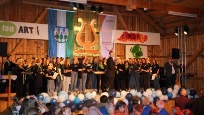 Bild: fvo
Die Chöre "tonART" und "amicanti" sowie Moderator Hans-Peter Reil (rechts) auf der Bühne beim Jubiläumskonzert des Gesang- und Orchesterverein Waldthurn in der Vereinshalle.