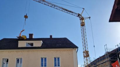 Bild: td
Ein Kran, der bei der Baustelle der Sparkasse (rechts) an der Postgartenstraße in Schwandorf benötigt wird, verursachte Mittwochabend Schaden am Dach des Nachbarhauses (links).
