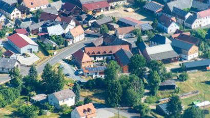 Luftbild: mür
Bei einer Bustour durch den Landkreis Tirschenreuth stand das Thema Flächensparen im Mittelpunkt. Besucht wurden erfolgreiche Beispiele, wie alte Gebäude neu genutzt und brachliegende Flächen wiederbelebt wurden – so wie der Mühlenhof Mähring (Bildmitte).