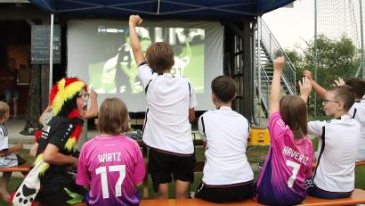 Bild: Thomas Dobler
Die Kinderbank ganz vorne vor der Leinwand ließ sich vom sportlichen Geschehen genauso mitreißen wie die Größeren dahinter.