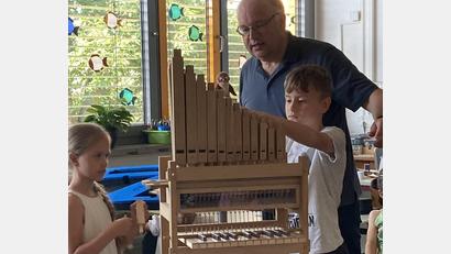 Bild: Michaela Meier/exb
Organist Bernhard Müllers mit zwei Schülern beim Erforschen der kleinen Orgel.