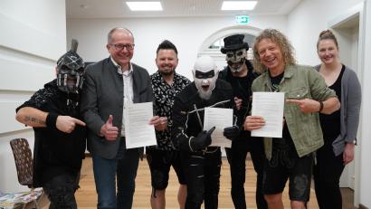 Bild: kaz
Die Metal-Band Hämatom feiert 2024 ihr 20-jähriges Bestehen mit einem Open-Air-Konzert auf dem Kemnather Stadtplatz. Die Verträge sind unterschrieben. Von links: Jacek "Ost" Zyla, Roman Schäffler, Thorsten "Nord" Scharf, Frank "Süd" Jooss sowie die Troglauer Mike Raps (Dritter von links), Thomas "Domml" Wöhrl (Zweiter von rechts) und Carolin Böckl vom Stadtmarketing.