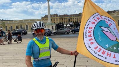 Bild: Reger
Josef Reger kurz vor dem Start in Wien bei Schloss Schönbrunn. Auf der Fahne ist das Logo des "Three Peaks Bike Race" zu sehen.
