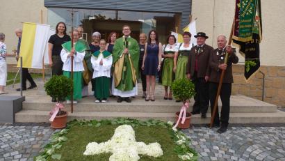 Bild: Bock/exb
Einen Blumenteppich hat der Pfarrgemeinderat vor der St.-Martins-Kirche gelegt. Die Mitglieder übergeben symbolische Geschenke. Die Hubertus-Schützen freuen sich über das Fahnenband.
