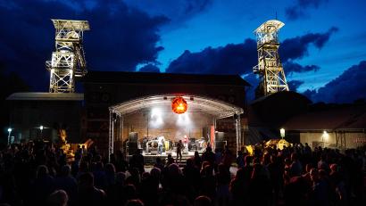 Bild: Brigitte Grüner/Förderverein Maffeispiele/exb
Das Classic-Rock-Festival G:O:A findet auf dem Gelände des Bergbaumuseums Maffeischächte statt. Neben der Bühnenbeleuchtung werden in der Dämmerung auch die Fördertürme beleuchtet.