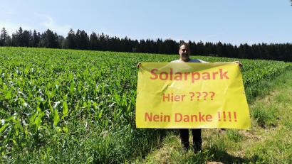 Bild: Portner
Markus Dums präsentiert ein Banner gegen den geplanten Solarpark in Mitterlangau, der sich zum großen Teil oberhalb seines Hauses bis hin zur Waldgrenze erstrecken würde.