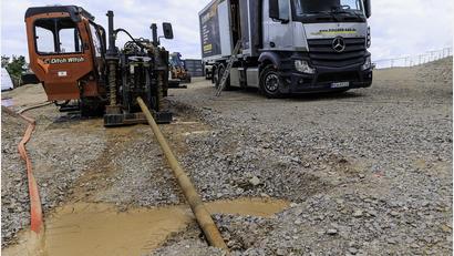 Bild: Hösamer
Mit dem Spülbohrgerät (links) wird das Gestänge (im Vordergrund) horizontal unterirdisch vorangetrieben. Bei Obersteinbach werden so über 200 Meter Länge in bis zu 11 Meter Tiefe überwunden. Im Lkw rechts wird unter anderem die Spülflüssigkeit vorbereitet.