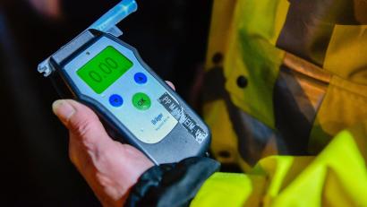 Symbolbild: Uwe Anspach/dpa
Ein Polizeibeamter hält ein Alkoholmessgerät mit der Aufschrift «0,00» in der Hand.