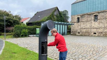 Bild: ihl
Durch achtmaliges Kurbeln lädt sich der Poesiomat vor dem Cebb in Schönsee auf. Er erzählt auf Knopfdruck oder spielt Musik.