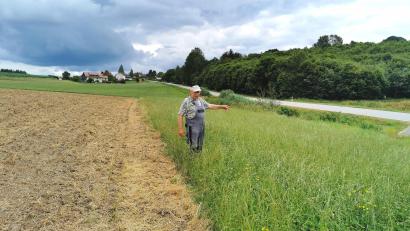 Bild: Portner
Austragslandwirt Andreas Reisinger aus Oberlangau/Oberviechtach zeigt auf den Grünland-Gewässerschutzstreifen zwischen Getreidefeld und Fluss Murach (neben Straße).