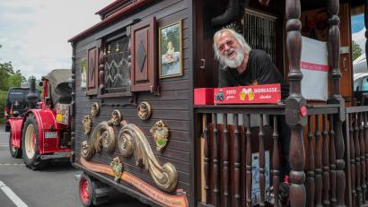 Bild: Wolfgang Steinbacher
Fritz Schmid auf der winzigen Veranda seines Oldtimer-Gespanns auf dem Wohnmobilstellplatz in Amberg. In der "Bierkasse", auf die das rote Schild hinweist, hinterlassen Passanten oft "Trinkgeld" für ein Foto.