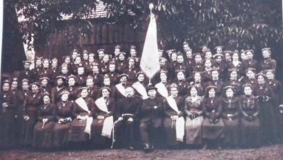 Bild: Archiv Werner Veigl/exb
Fahnenweihe der Marianischen Jungfrauenkongregation am 8. September 1918. 65 Jungfrauen in Festkleidung stellten sich stolz dem Fotografen. Vorne in der Mitte Pfarrer Franz Seraph Perlinger (mit Hut). Die Vereinsfahne war ein Symbol der Gemeinschaft, das alle Feste und Feiern des Ortes und der Pfarrgemeinde begleitete. Es war aber auch die Fahne, mit der Vereinsmitglieder in Trauer und Anteilnahme Verstorbener das letzte Geleit gaben.