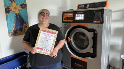 Bild: Matthias Bäumler
Michaela Sack mit ihrem Tatortreiniger-Zertifikat und ihrem ganzen Stolz: der Spezialwaschmaschine Berta.