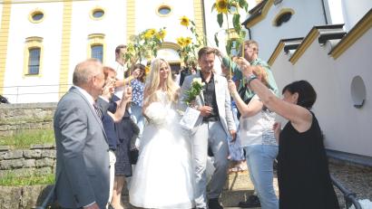 Bild: bey
Thomas und Magdalena Wagner durchschreiten nach der Trauung in der Kreuzbergkirche Pleystein ein Spalier aus Sonnenblumen.
