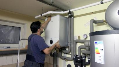 Symbolbild: Doreen Garud/dpa
Ein Handwerker befestigt die Abdeckung an einer Steuereinheit einer Wärmepumpe im Keller eines Wohnhaues. Mit der Energiewende verändert sich auch der Beruf des Heizungsbauers.