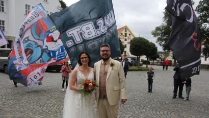 Bild: kro
Jessica und Nico Bergauer vor den wehenden Fahnen des Selber-Wölfe-Fanclubs „Fanatics 2003“, dessen Vorsitzender der Bräutigam ist.
