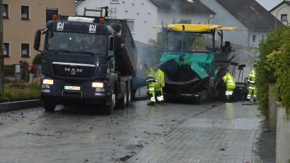 Bild: dob
Bei strömendem Regen haben Arbeiter am Donnerstag die Tragschicht in der Kößlmühlstraße aufgebracht. Bei geeignetem Wetter soll dann die Tragschicht folgen.