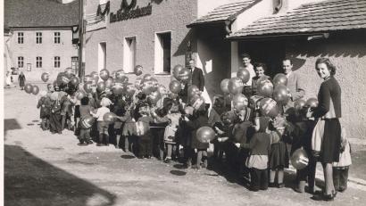 Repro: Archiv Böhm
Erinnerungen an den Raiffeisenverein: Bis zum Neubau der Bank zum Ende der 60er-Jahre war die Bank im Obergeschoss des Kaufhauses Leuthner in der Hammerstraße untergebracht. Alle Jahre gehörte damals als besonderes Ereignis der Weltspartag dazu, zu dem immer die Kindergartenkinder eingeladen waren. Der Zweite von rechts ist der damalige Bankvorstand und Bürgermeister Anton Rogg. Das Bild entstand zum Ende der 50er-Jahre.
