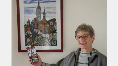 Bild: Martina Heberl/exb
Bärbel Eichenmüller vom Weltladen-Team mit der neuen Auerbach-Schokolade vor dem Bild, das Sr. Liselotte Schuhmann gemalt und als Motiv für die Tafel zur Verfügung gestellt hat.