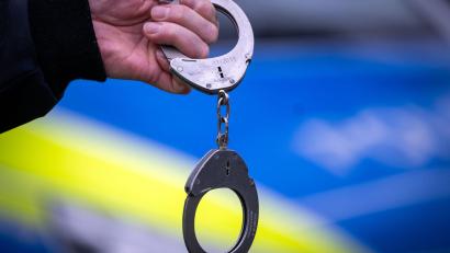 Symbolbild: Soeren Stache/dpa/Symbolbild
Ein Polizist hält ein Paar Handschellen. In Schwandorf wurde ein Mann festgenommen.