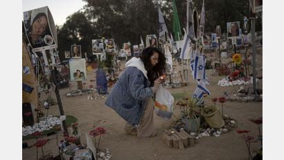 Bild: Maya Alleruzzo/dpa
Eine Frau zündet am jüdischen Feiertag Simchat Tora, der im hebräischen Kalender ein Jahr nach dem Anschlag begangen wird, in der Nähe des Kibbuz Re'im im Süden Israels nahe dem Gazastreifen Kerzen auf dem Gelände des Nova-Musikfestivals an, bei dem Hunderte von Feiernden von der Hamas getötet oder entführt wurden.