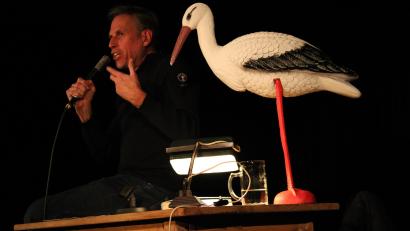 Bild: prh
Radiomoderator Achim "60" Bogdahn las auf dem Schafferhof aus seinem Buch "Unter den Wolken". Seine 125. Lesung war höchst amüsanten und kurzweilig. Immer dabei ein Plastikstorch, das Geschenk eines Buchhändlers, der mittlerweile auch Bahnfahren gewöhnt ist.
