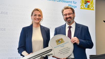 Bild: Petra Hartl
Bei der Amtseinführung des Präsidenten des Bayerischen Landesamtes für Pflege überreichte die Bayerische Staatsministerin für Gesundheit, Pflege, Judith Gerlach (CSU), den Schlüssel für das Amt an Bernhard Scheibl.