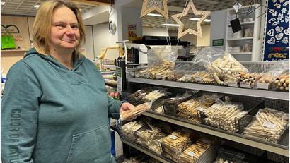Bild: ihl
Ingrid Müller hält eine Packung Seidenklöppel in der Hand. Im Regal zeigt sich die Auswahl, von Klöppel mit und ohne Hülse bis hin zum Wollklöppel.