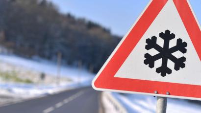 Symbolbild: Uwe Anspach/dpa-tmn
Dieses Warnschild weist auf einer Straße auf Straßenglätte hin.