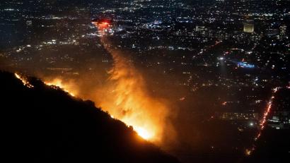 Bild: Ethan Swope/AP/dpa
Ein Hubschrauber wirft Wasser auf das brennende Sunset Fire in den Hollywood Hills.