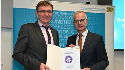 Bild: Staatsministerium für Gesundheit und Pflege/exb
Schulleiter Hans-Jürgen Bruhn (links) freut sich über die Urkunde, die ihm Dr. Rainer Hutka (rechts), Amtschef des Staatsministeriums für Gesundheit und Pflege, überreichte.