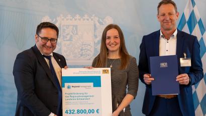 Bild: Wirtschaftsministerium/E.Neureuther/exb
Wirtschaftsstaatssekretär Tobias Gotthard (links) überreicht Regionalmanagerin Veronika Kiener und Sachgebietsleiter Christian Meyer den Förderbescheid.