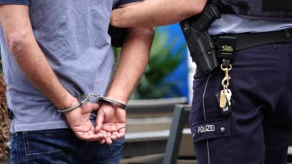 Symbolbild: Johannes Neudecker
Ein Mann wird von einem Polizeibeamten verhaftet und abgeführt.