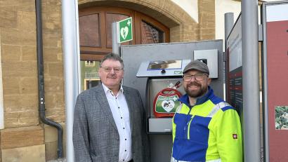 Bild: Stefanie Gradl
Bürgermeister Hans-Martin Schertl (links) dankt Bauhofmitarbeiter Michael Nutz für die Installation des Defibrillators beim Rathaus.