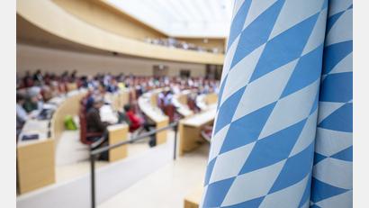 Symbolbild: Peter Kneffel/dpa
Die weiss-blaue Fahne hängt während einer Sitzung im Plenarsaal des bayerischen Landtags.