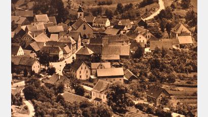 Bild: Archiv Heimat- und Kulturverein Freudenberg
Dieses Luftbild diente als Vorlage für das Bild: Wutschdorf in den 1950er-Jahren. Damals standen noch viele alte Bauernhäuser, unter anderem beim Ochsenwirt, beim Kochschreiner und beim Bojerhansl.