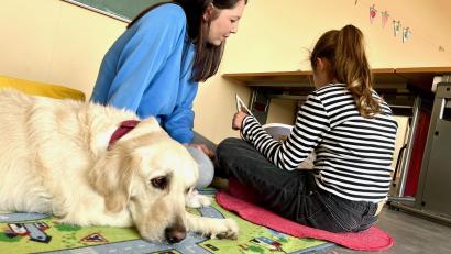 Bild: Gabi Schönberger
Lesehund Ella ist mit Besitzerin Marina Vogel regelmäßig in der Grundschule Mantel. Schülerin Greta liest der Hündin aus einem Buch vor.
