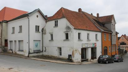 Bild: bjp
Im Doppelanwesen Reinwaldstraße 7 und dem straßenabwärts angrenzenden repräsentativen "Rauchhaus" will die Stadt Pressath ein Bürger- und Kulturzentrum einrichten. Der obere Bauteil des "weißen Hauses" (links) soll einem Neubau in historisierendem Stil weichen.