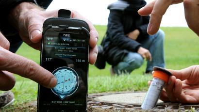 Symbolbild: Ingo Wagner/dpa
Geocacher haben mithilfe eines GPS-Geräts ein in einer Röhre verpacktes Mini-Logbuch in einem Kanaldeckel gefunden.